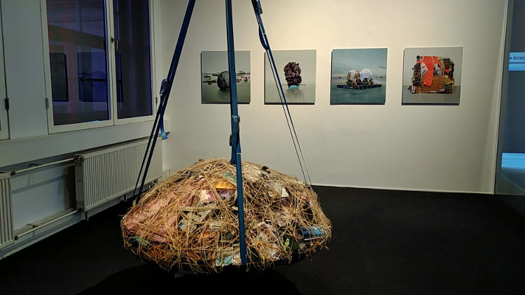 Installation "Pendulum" von Mary Mattingly, dahinter an der Wand Fotos der gleichen Künstlerin. Höhenrausch Linz 2018. Wanderhunger