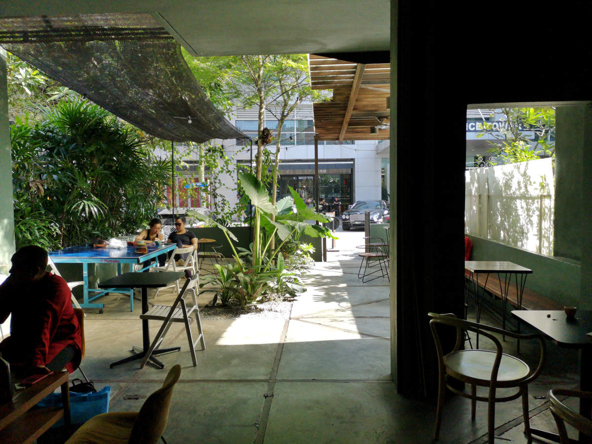 Der Eingang und Garten mit Sitzplätzen des Feeka Coffee Roasters in Kuala Lumpur. Wanderhunger