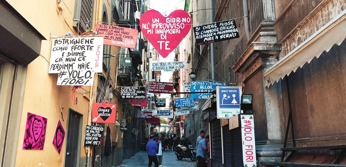 Kleine Gasse im spanischen Viertel mit Schildern und Hund am Wochenende in Neapel
