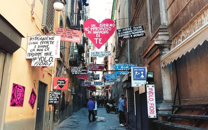 Kleine Gasse im spanischen Viertel mit Schildern und Hund am Wochenende in Neapel