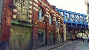 Starker Farb- und Materialkontrast zwischen moderner blauer Stahlbrücke und rotem Backsteinhaus in London. Fotoparade 01/2018 auf Wanderhunger