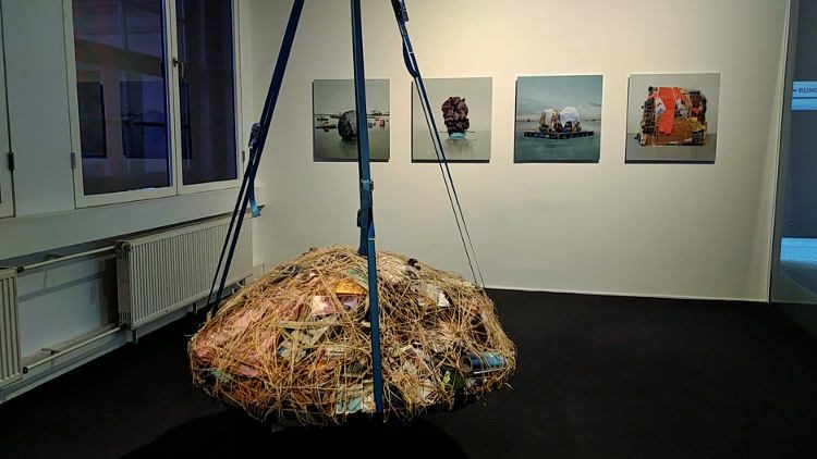Installation "Pendulum" von Mary Mattingly, dahinter an der Wand Fotos der gleichen Künstlerin. Höhenrausch Linz 2018. Wanderhunger