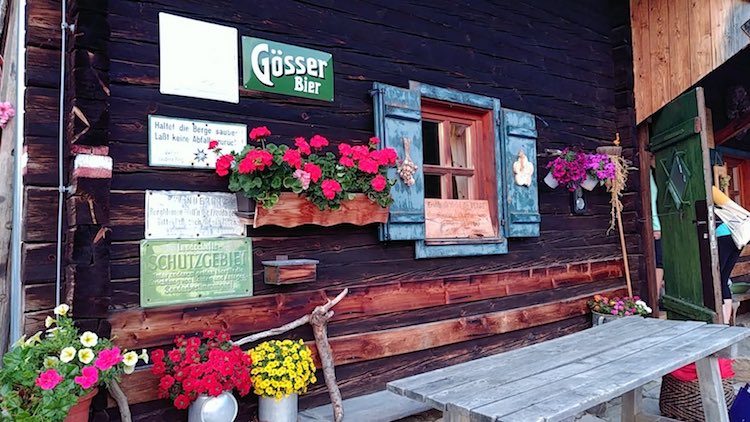 Gemütlicher Tisch vor der hübsch dekorierten Vorderseite der Schönwetterhütte. Wanderhunger