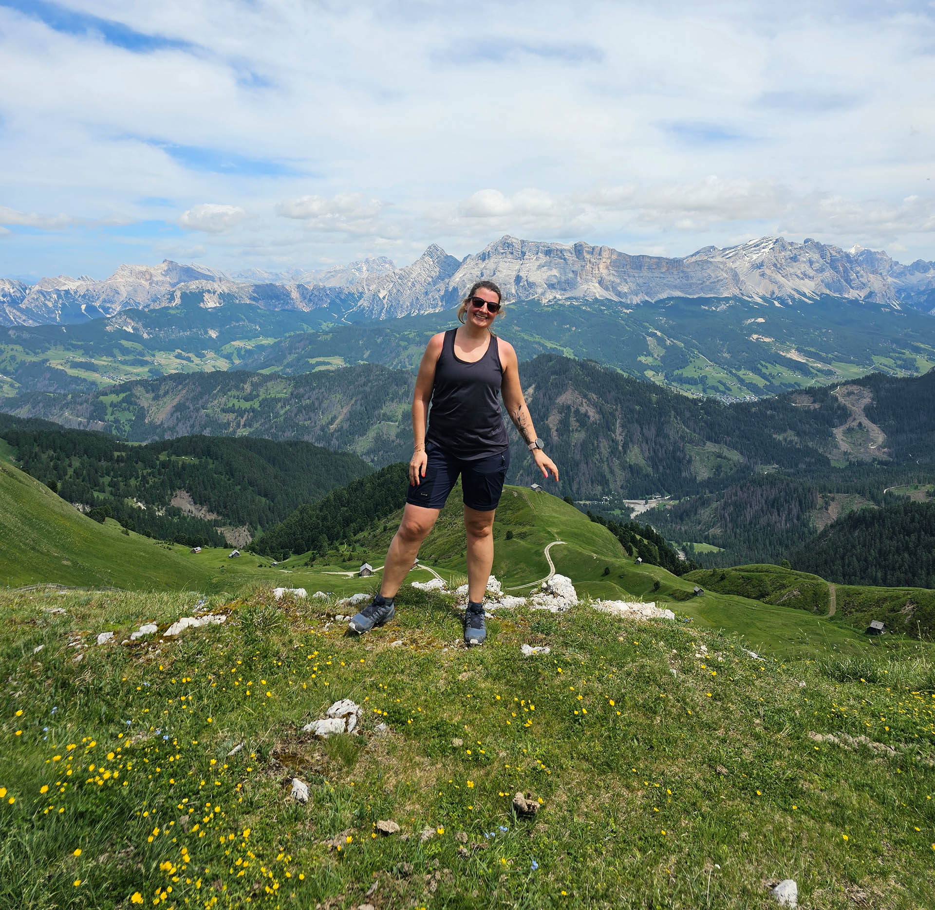 Eine Frau posiert auf einer Almwiese vor Gebirge