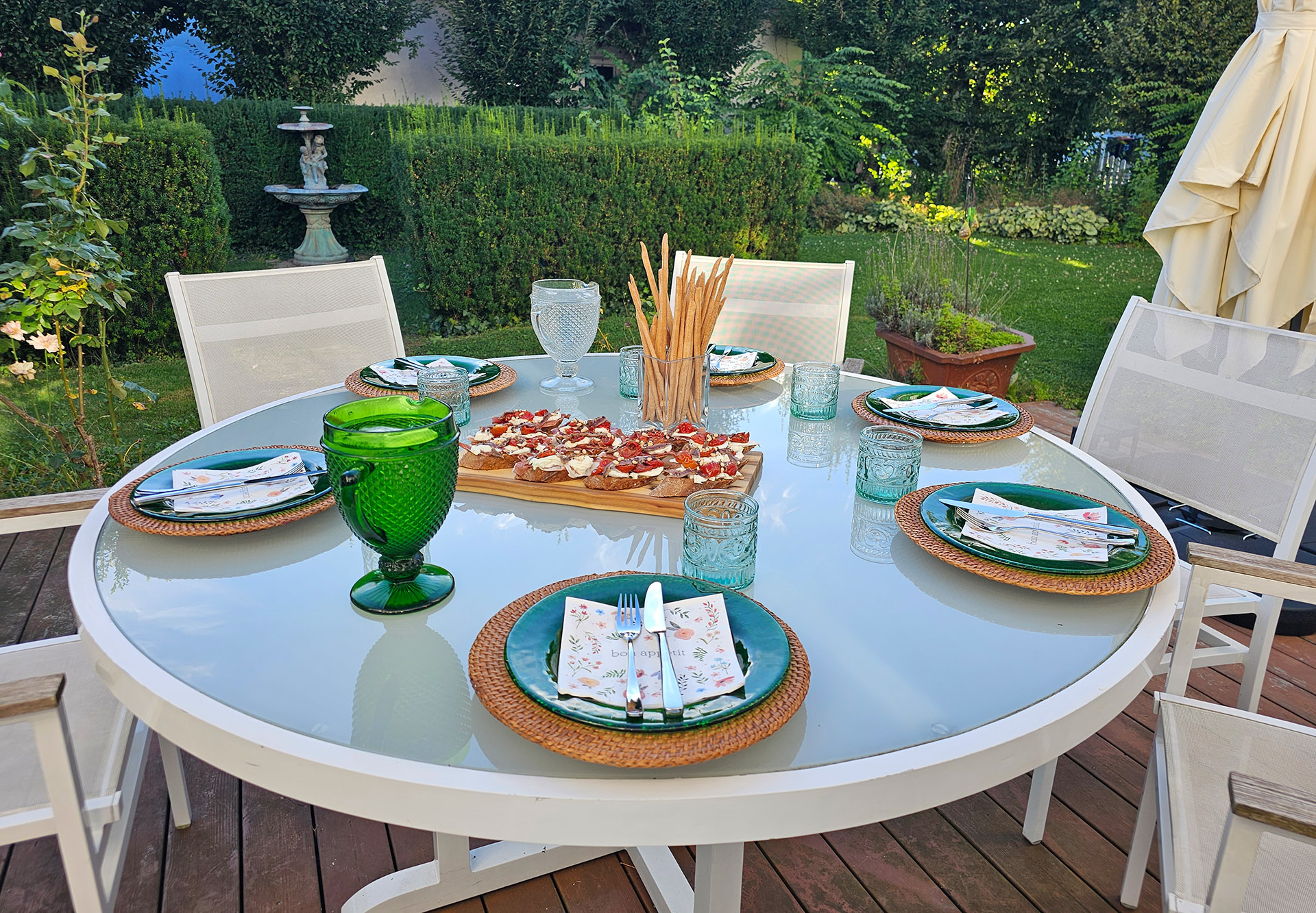 Ein sommerlich gedeckter Tisch auf der Holzterrasse im Garten