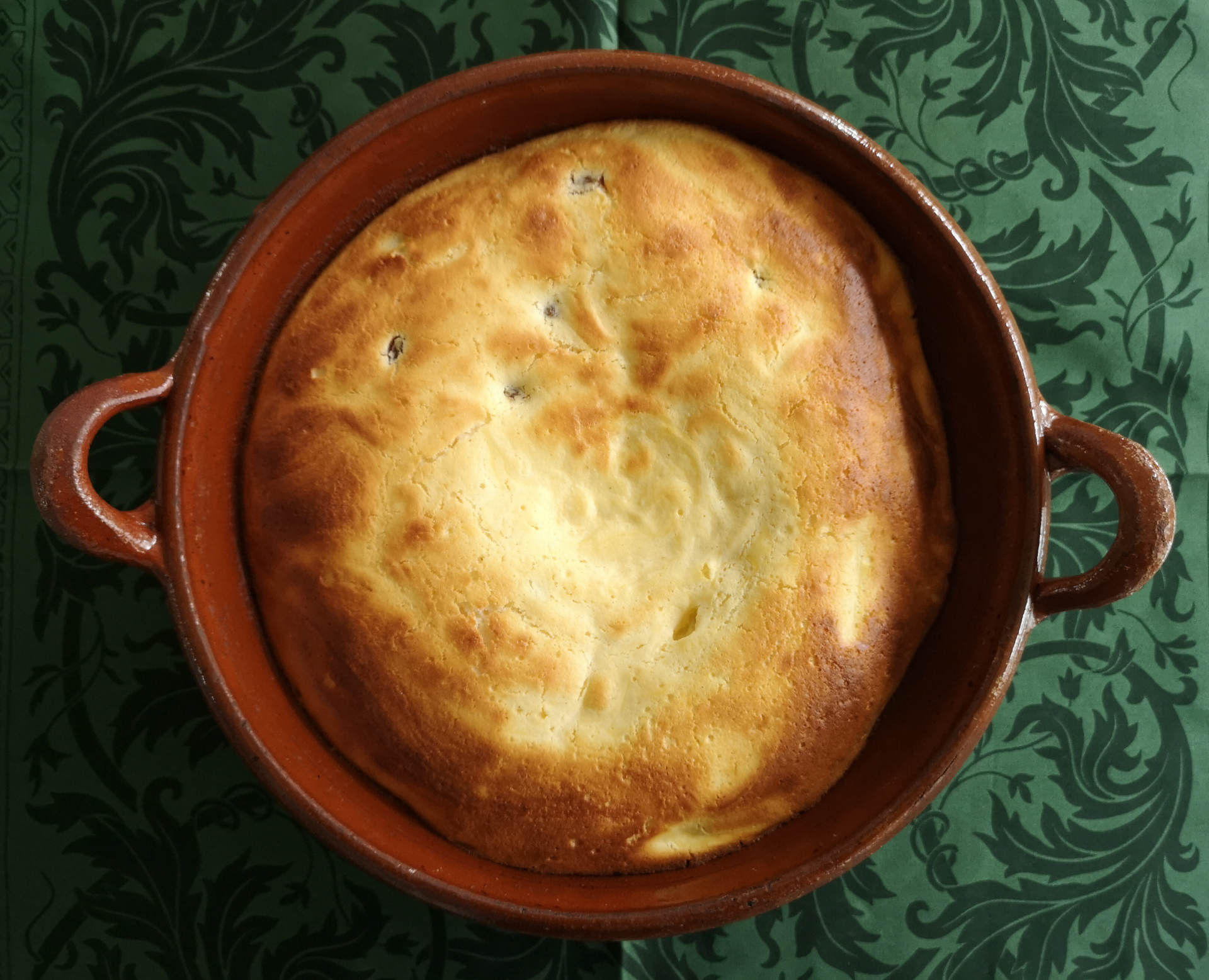 Auflauf in brauner Keramikschüssel auf grünem Tischtuch