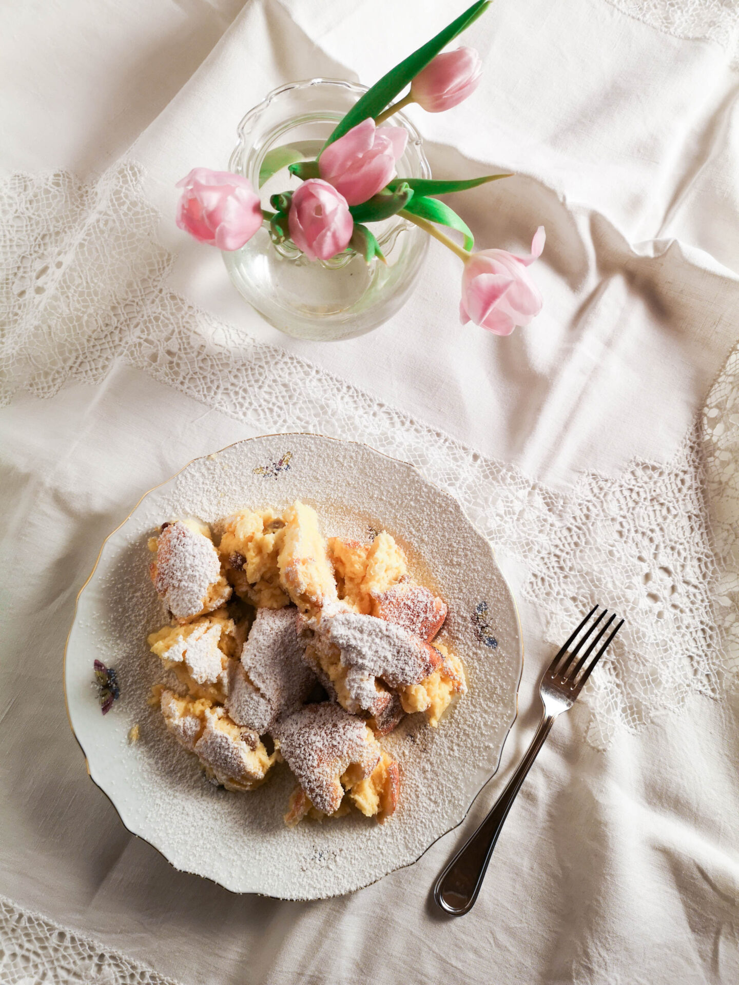 Gebackener Topfenschmarren mit Staubzucker bestreut und weißem Teller mit Tischtuch