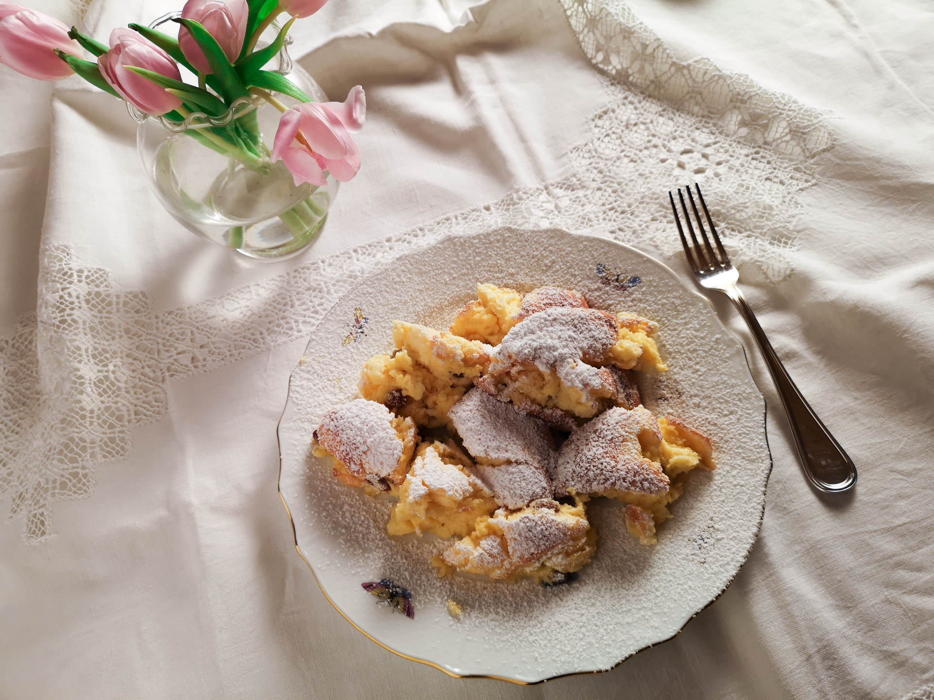Gebackener Topfenschmarren mit Staubzucker bestreut und weißem Teller mit Tischtuch