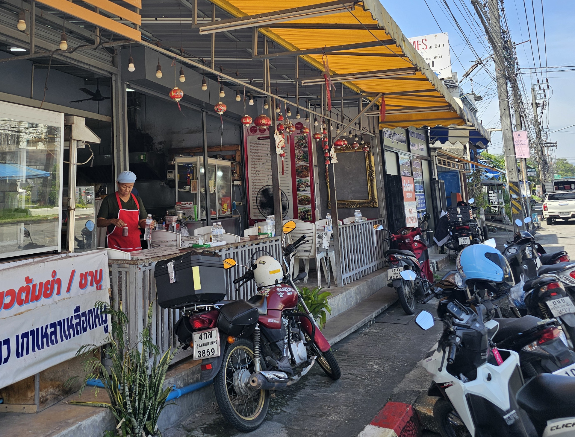 Offenes thailädnisches Restaurant, davor geparkte Motorroller